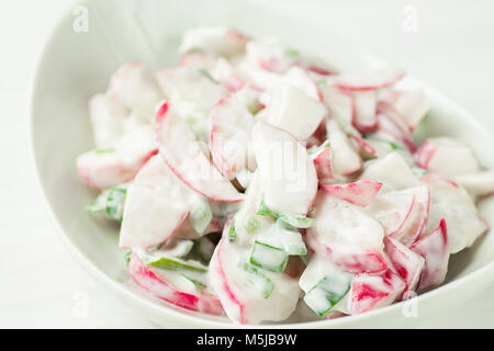 Healthy Red Radish and Green Scallion Onions Salad with Greek Yogurt Dressing in White Serving Bowl Standing on Wood Kitchen Table. Easter Brunch Meal Stock Photo