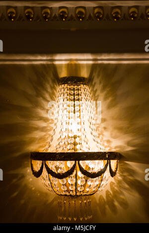 Luxury chandelier on wall in golden ballroom, close up Stock Photo