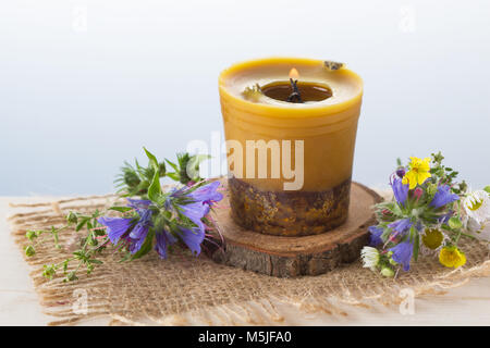 Handmade beewax burning candle and grass blossoms Stock Photo