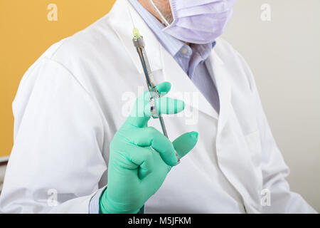 Male dentist with mask holding  local anesthetic injection preparing for treatment Stock Photo