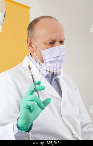 Male dentist with mask holding  local anesthetic injection preparing for treatment Stock Photo