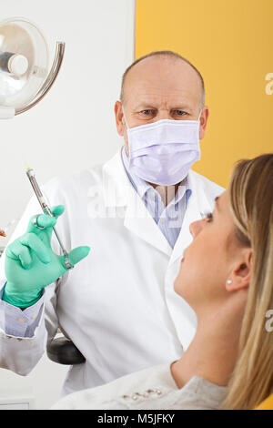 Dentist holding anesthetic injection preparing for dental treatment on female patient Stock Photo