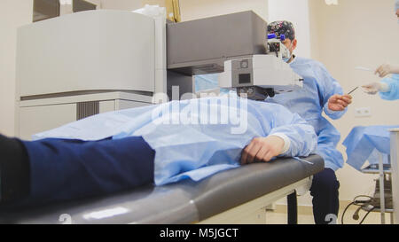 The patient lies on the operating surgical table during ophthalmology operation surgery wthout anesthesia - laser vision correction Stock Photo