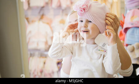 Portrait of happy blonde child girl doing shopping in kids dress store Stock Photo