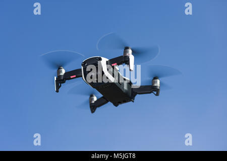 A DJI Mavic Air drone in flight against a blue sky Stock Photo