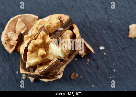 Top view close-up picture of nutritious tasty dry cracked walnuts on dark background, shallow depth of field, selective focus, macro. Seasonal nuts. O Stock Photo