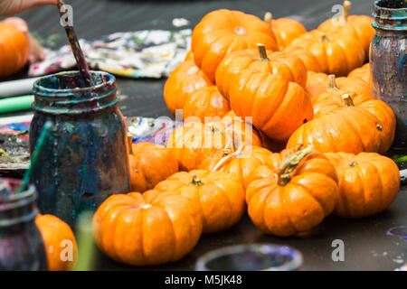 Miniature pumpkins sit on arts and crafts table waiting to be painted at fall festival. Stock Photo