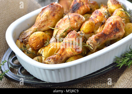 Fresh from the oven: Baked chicken drumsticks with small potatoes and onions Stock Photo