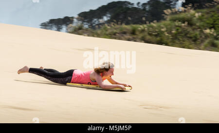 Lady Sandboarding Down te Paki Dunes, New Zealand Stock Photo