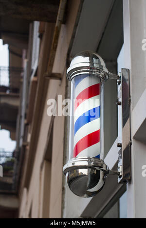 closeup of barber shop pole sign with blue and red moving stripes on a building facade Stock Photo