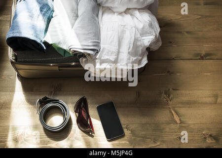 Open suitcase with female clothes for trip on the floor. Stock Photo