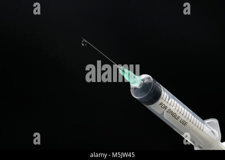 Plastic syringe close-up with drop isolated on black Stock Photo