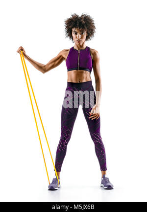 Strong girl using a resistance band in her exercise routine. Young african girl performs fitness exercises on white background. Strength and motivatio Stock Photo