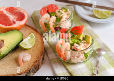 Cocktail salad with shrimp, avocado, green lettuce, grapefruit and mayonnaise sauce in a glass. Stock Photo