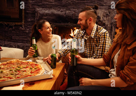 Smiling people in casual clothes eating pizza and drinking beer Stock Photo