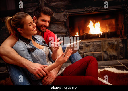 Happy couple in love hugging and using tablet together at home Stock Photo