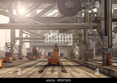 Automated Guided Vehicles moving shipping containers to and from gantry cranes in a port container terminal. Stock Photo