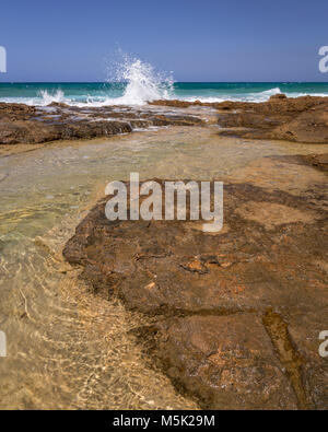 Rocky beach and pool at Malia on the Mediterranean coast of Crete with wave splash Stock Photo