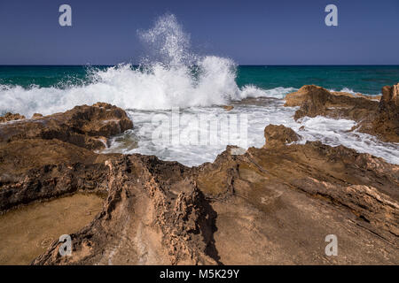 Rocky beach and wave splash at Malia on the Mediterranean coast of Crete Stock Photo