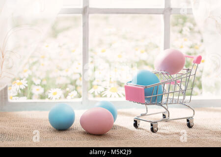 Easter shopping theme: colorful eggs in a cute shopping cart on sunny window Stock Photo