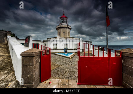 Lighthouse Farol da Ponta do Arnel at the sea, dark clouds, north-east, Sao Miguel, Azores, Portugal Stock Photo