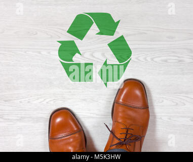 Classic men's elegant shoes standing on a white wooden floor with a green recycling symbol painted on it Stock Photo