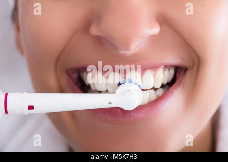 Close-up Of A Woman Brushing Teeth Using Electric Toothbrush Stock Photo