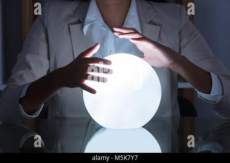 Close-up Of Businesswoman Hand On Crystal Ball On Table In Office Stock Photo