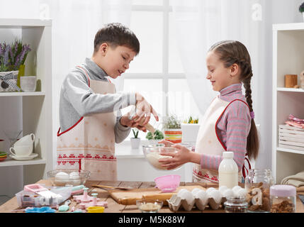 Girl and boy cooking in home kitchen, make the dough for baking, healthy food concept Stock Photo