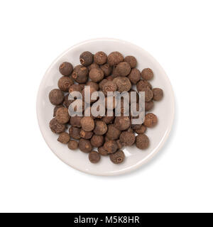 Seeds of allspice in a white bowl on a white background. Stock Photo