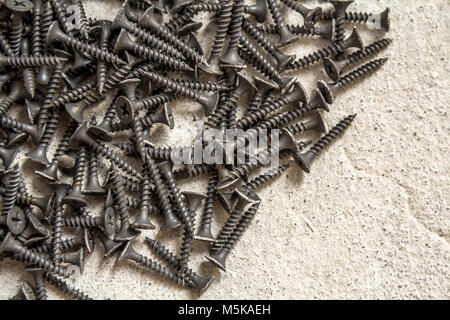 Close-up image of many small black screws on concrete background Stock Photo
