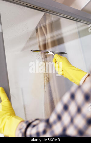 Mature man cleaning windows using squeegee Stock Photo