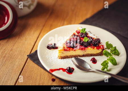 Beautiful traditional italian cheesecake with red fruits, mint, and powdered sugar on wooden background, selective focus Stock Photo
