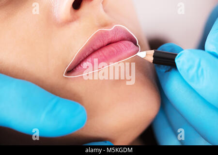 Cosmetologist Applying Permanent Make Up On Young Woman's Lips Stock Photo