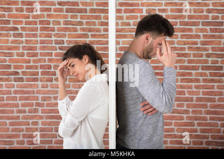 Depressed Contemplated Young Couple Against Brick Wall Stock Photo