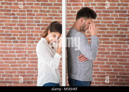 Depressed Contemplated Young Couple Against Brick Wall Stock Photo
