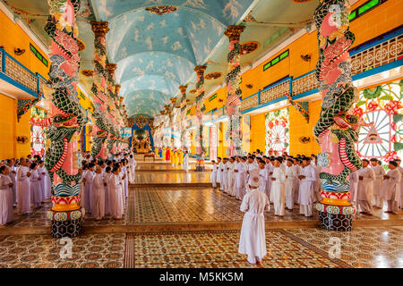Inside Cao Dai Holy See Temple, Tay Ninh province, near ho chi minh city, Vietnam and meditating followers of the Cao Dai religion Stock Photo