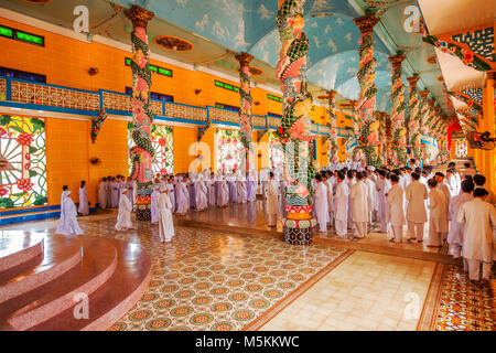 Inside Cao Dai Holy See Temple, Tay Ninh province, near ho chi minh city, Vietnam and meditating followers of the Cao Dai religion Stock Photo