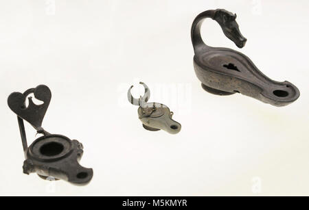 From left to right: lamp with heart shaped plate, from Cologne; pendant lamp with lid, from Luxembourg Street, Cologne; and lamp with handle in the shape of horse head, of unknown origin. Roman-Germanic Museum. Cologne. Germany. Stock Photo
