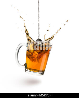 glass cup of tea with infuser splash inside, on white background. Stock Photo