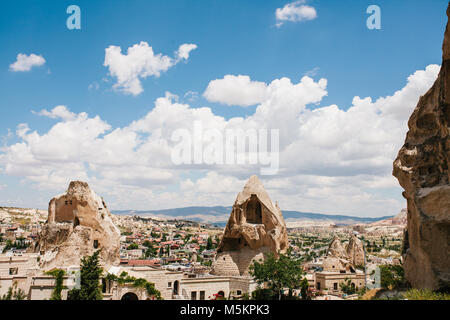 Beautiful scenery of Goreme in Turkey, small houses in the midst of bizarre rocks on sunny warm day with white cumulus clouds Stock Photo