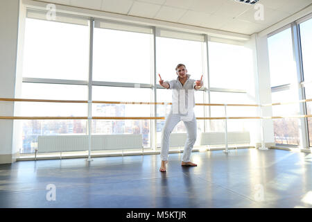 Young blonde dancer enjoys winning in white suit and makes warm  Stock Photo