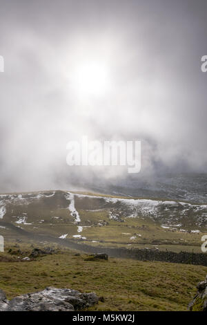 Patches of snow on fields seen through low clouds near the Settle Loop in theYorkshire Dales Stock Photo