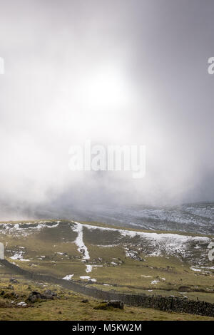 Patches of snow on fields seen through low clouds near the Settle Loop in theYorkshire Dales Stock Photo