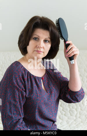 woman with a massage comb brushes her hair Stock Photo