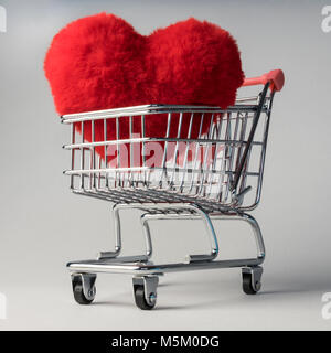 Heart shape red fluffy soft pillow or cushion in shopping trolley cart, price cost of love, shopping for love, finding love in shop, valentine's day Stock Photo