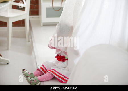 Portrait of little girl peeking from curtains at home Stock Photo