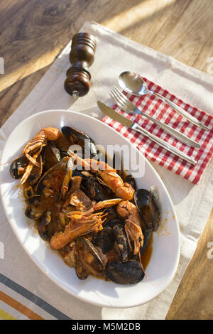 fish soup with prawns mussels and mixed fish in a serving dish Stock Photo