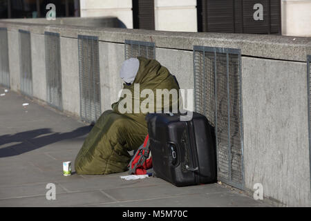 London, UK, 24 Feb 2018. A vagrant wraps up warm in a sleeping bag on a Sunny day with clear blue skies as he sits on London Bridge. The weather is forecast to get colder early next week as the winds come from Siberia©Keith Larby/Alamy Live News Stock Photo
