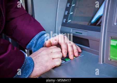 Hands typing PIN at ATM machine for cash money withdrawal. Close up for hands typing on ATM maschine. Stock Photo
